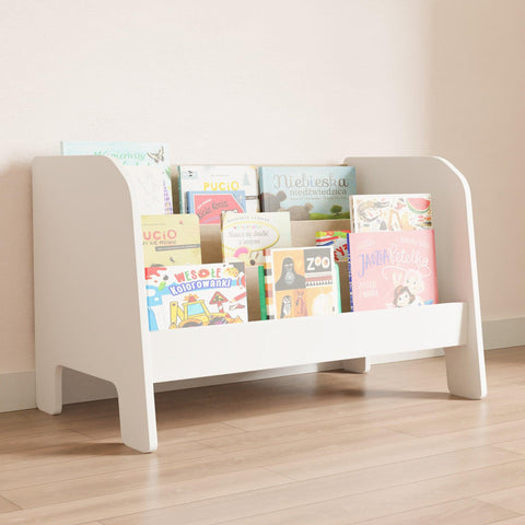 White montessori low bookshelf. On the bookshelf stacked children's books with the covers facing forward.