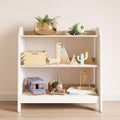 Children's bookcase with three shelves, white sides and wooden shelves. The bookcase holds a variety of children's toys.