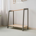The image showcases a Montessori-style clothing rack featuring a sophisticated grey and natural wood finish. The frame is painted in a soft grey tone, which harmonizes beautifully with the natural wood hanging rod and bottom shelf, offering a contemporary aesthetic ideal for modern nurseries or children’s rooms. This design not only enhances the decor but also serves as a functional piece, promoting independence and organization in children. 
