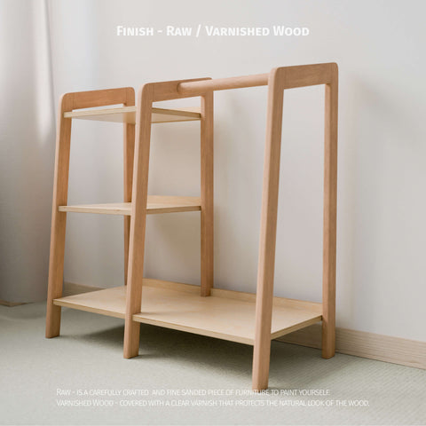 The image displays an empty Montessori-style wardrobe with a finish option of either raw or varnished wood. The wardrobe features a natural wood frame with a hanging rod and shelving, providing practical storage for children's clothing. The raw wood is finely sanded, ready for painting or personal finishing, while the varnished wood option offers protection and enhances the natural grain.