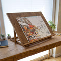 Adjustable wooden desk easel displaying a painting canvas on a desk in a sunny workspace