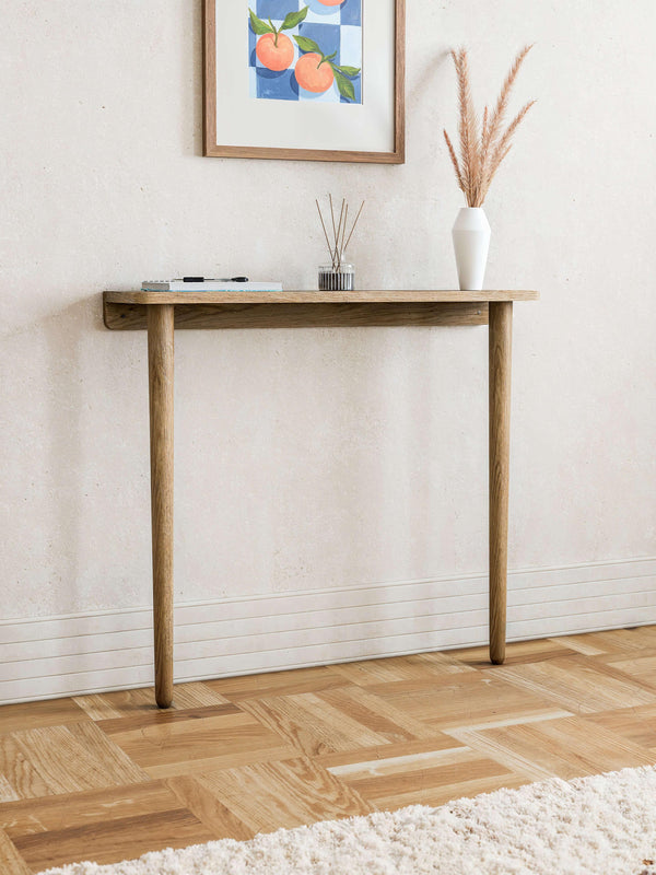 Mid-century modern console table in natural wood with two rounded legs, mounted to the wall in a minimalist hallway interior.