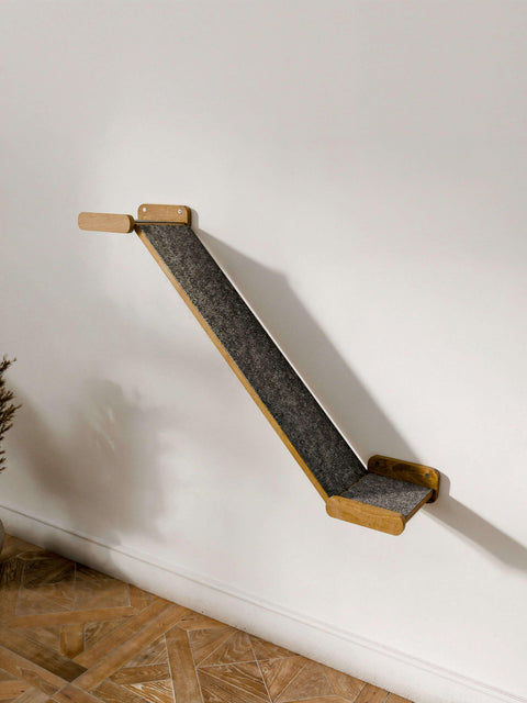 Side view of a single Minimalist Cat Bridge installed on a white wall, showing the dark oak wood finish and grey felt ramp surface. A functional Wall-Mounted Cat Climber setup.